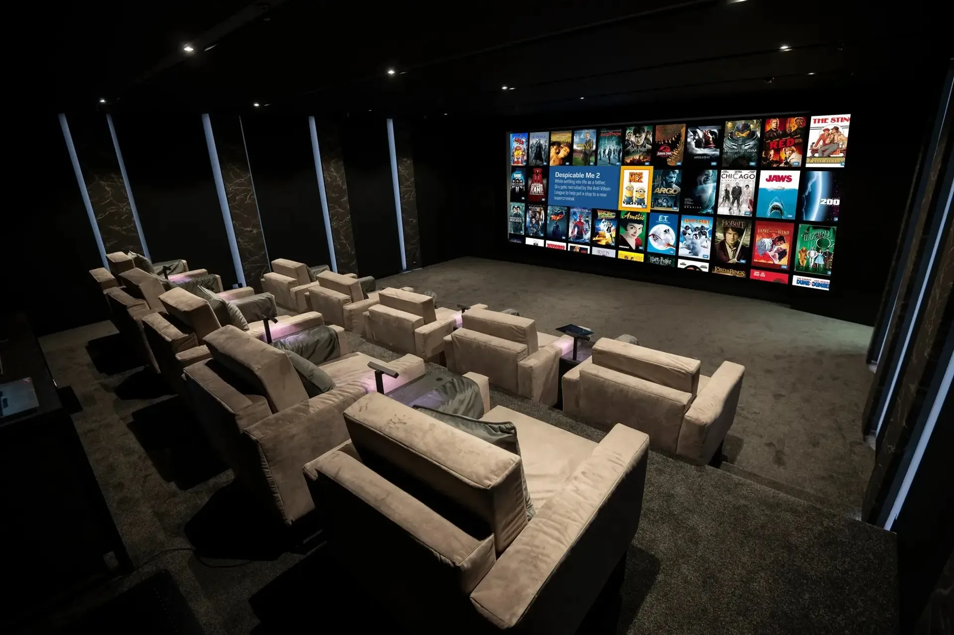 Dark dedicated home cinema room with rows of custom seating